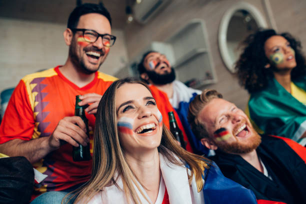 istock Joyful soccer enthusiasts supporting different teams while watching game on TV 952796792