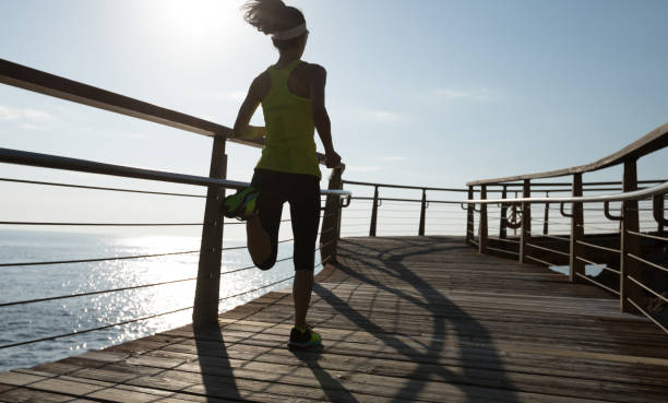 istock sporty female runner running on seaside boardwalk during sunrise 952797674