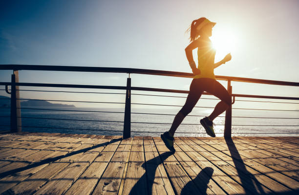 istock sporty female runner running on seaside boardwalk during sunrise 952798002