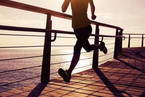 istock sporty female runner running on seaside boardwalk during sunrise 952800488