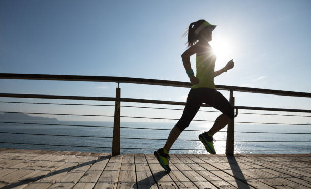 istock sporty female runner running on seaside boardwalk during sunrise 952804578