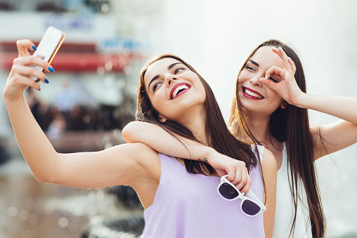 Two beautiful girls do selfie on the street