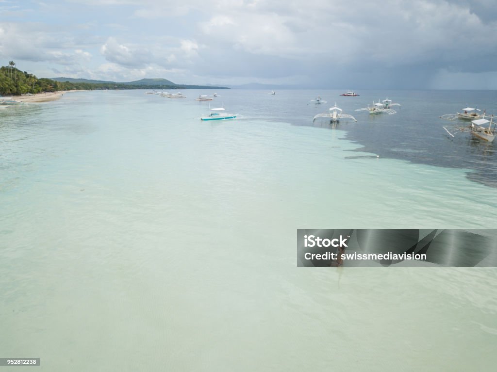 Aerial view of happy man relaxing in tropical sea, beach vacations concept Drone point of view aerial view of young man relaxing in the sea, tropical climate, white sand beach and turquoise water. People travel holiday concept. Shot in the Philippines 20-29 Years Stock Photo