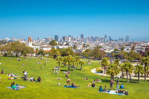Panorama view of people enjoying the sunny weather on a beautiful day with clear blue skies with the skyline of San Francisco in the background, California, USA