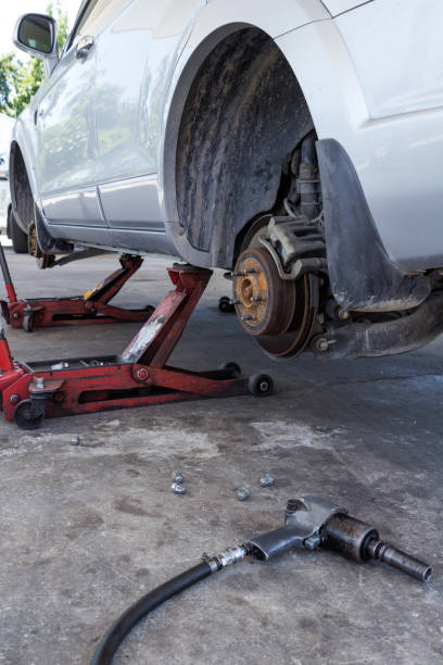 istock Tire replacement service fitting by hand jack with pneumatic wrench 952837066