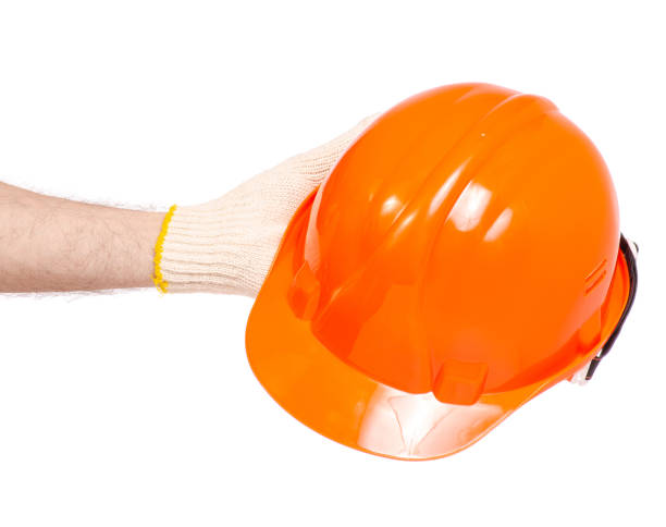 istock Orange man's helmet man's hand in a glove 952871230