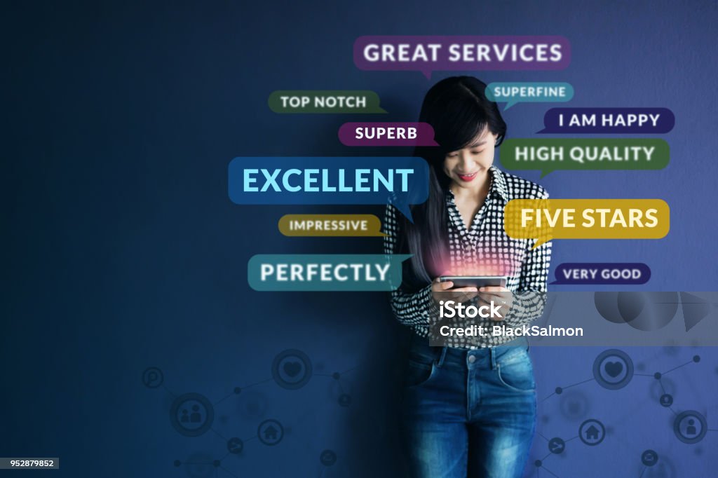 Customer Experience Concept. Soft focus of Happy Client standing at the Wall, Smiling while using Smartphone. Surrounded by Positive Review in Speech Bubble and Social Network icons Customer Stock Photo