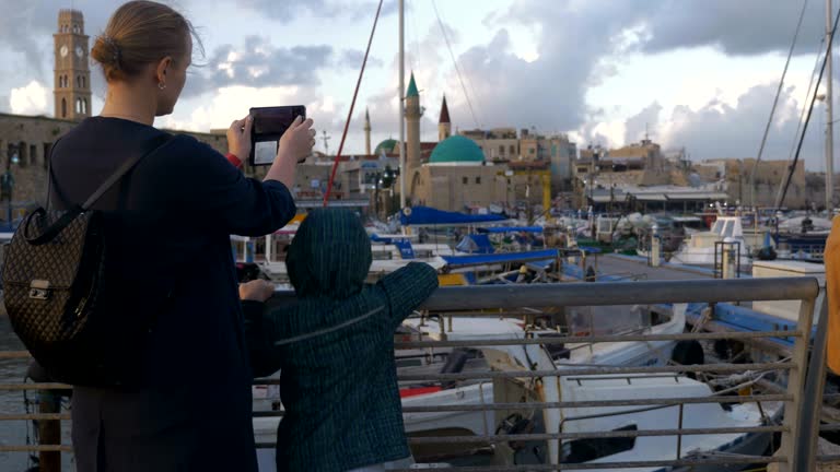 Woman with son taking photos when visiting Acre port, Israel