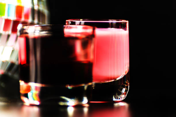 A close-up of a person's hand holding a glass of dark tea, illuminated by a beam of sunlight that creates a glowing amber color against a dark background
