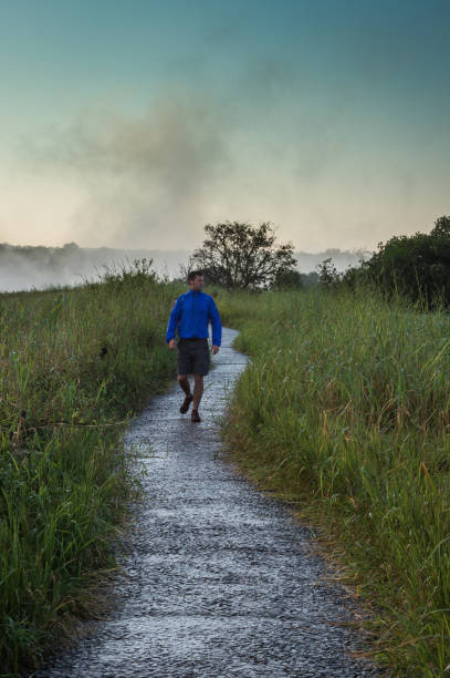 istock Man walking towards on footpath in the wet looking away 952922858