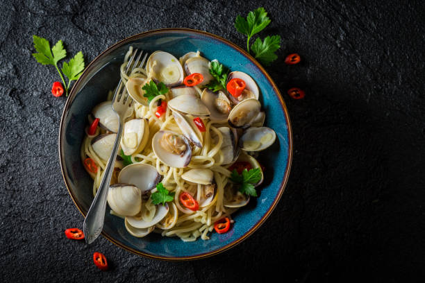 spaghetti vongole con vongole, peperoni e prezzemolo su roccia nera - linguine foto e immagini stock