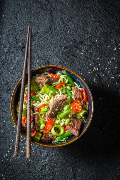 istock Hot asian noodle with beef and vegetables on black table 952958948