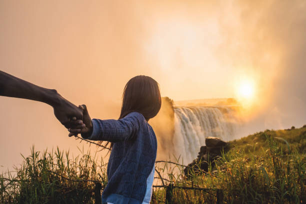 istock Holding hands pulling and looking towards a sunrise over Victoria Falls 952965656
