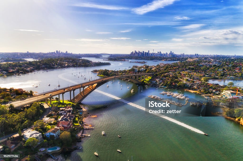 D Sy Gladesville Br 2 CBD Boat Colourful aerial view over Parramatta river and Gladesville bridge on Victoria road towards Sydney city CBD skyline. Speed boat beats the city traffic on open river water. Sydney Stock Photo