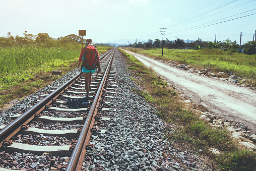 Asian woman travel countryside. Travel relax. bag backpack travel. Walk on the railroad. Thailand