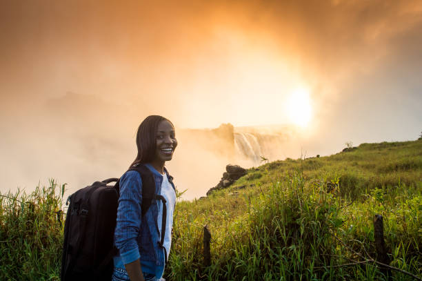 istock Woman with backpack looking at Victoria Falls at sunrise 952987972