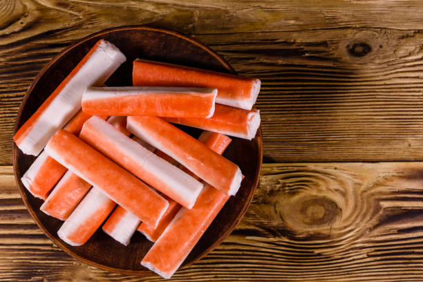 Ceramic plate with crab sticks on wooden table. Top view stock photo
