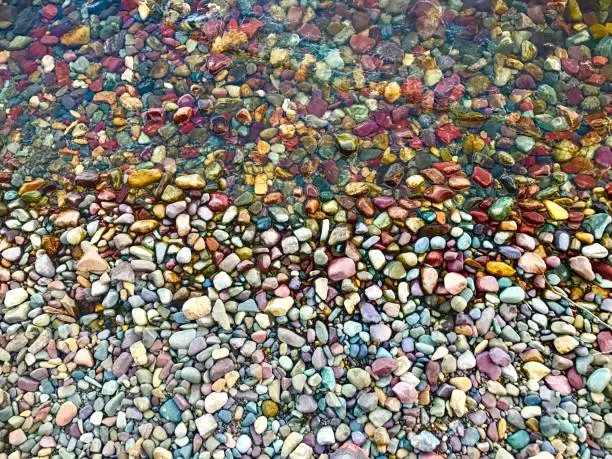 top-down view of wet and dry colorful rocks on the shoreline of Lake McDonald in Montana, USA