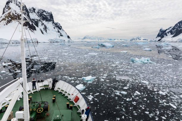 istock A ship travels through snow covered mountains and water filled with ice, while passengers look on, Lemaire Channel, Antarctica 953005918