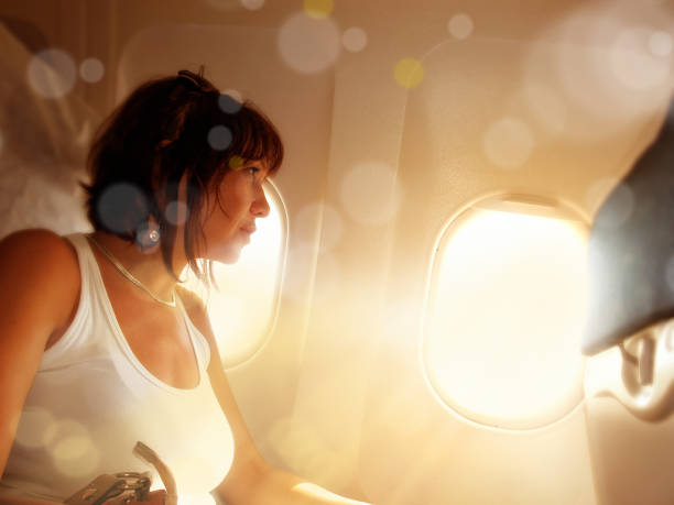 istock woman looking from airplane window and light beam 953023860