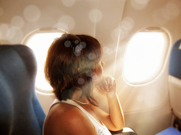 istock woman looking from airplane window and light beam 953023864