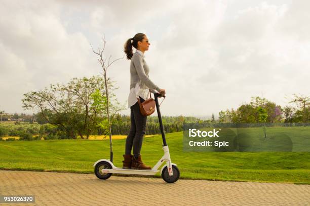 A Young Women With An Electric Scooter In The Park Stock Photo - Download Image Now - Electric Push Scooter, Motor Scooter, Bicycle