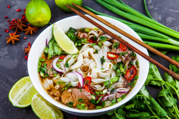 Vietnamese Beef Noodle Soup Pho Bo with beef on dark background Pho Bo - Vietnamese fresh rice noodle soup with beef, herbs and chili. Vietnam's national dish. lime basil plant stock pictures, royalty-free photos & images