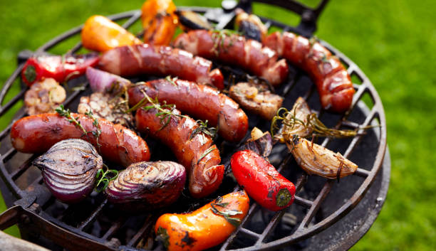 salchichas a la parrilla y verduras en un plato a la plancha, al aire libre. - sausage bratwurst barbecue grill barbecue fotografías e imágenes de stock