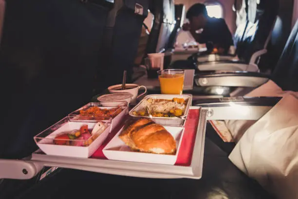 Tray of food. The passenger eats food on Board the plane on the background of the window. Meals on the plane. Different sets of food on the folding table.
