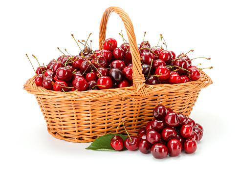 Sweet cherries (Prunus avium) in wicker basket on white