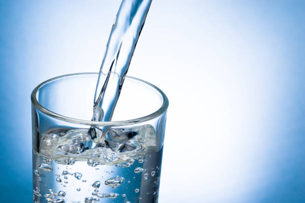 istock Pouring water into glass on blue background 953036194