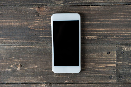 Directly above view of a smart phone over a wooden background.