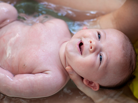 Happy month old baby enjoys his bath