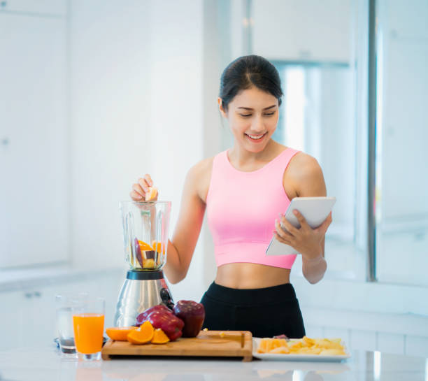 señora asiático hacer bebidas de frutas por uso de la tableta - instructor one person fruit drinking fotografías e imágenes de stock