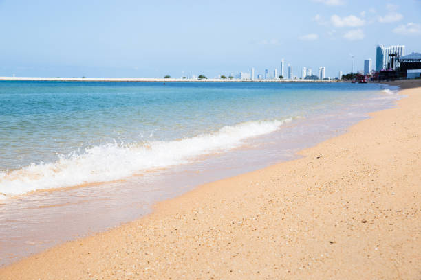 istock Beautiful clean beach and soft wave with modern building 953056056