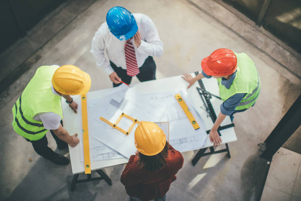 istock Architects and engeneers looking at blueprints at construction site 953056978
