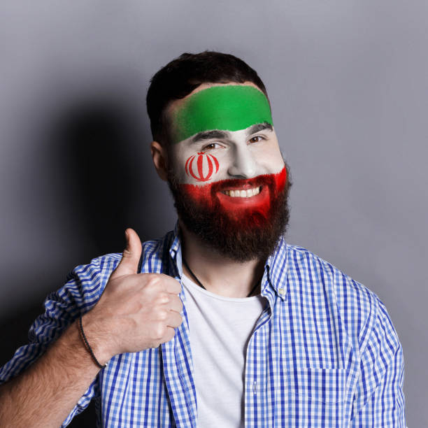 istock Young man with Iran flag painted on his face 953058246