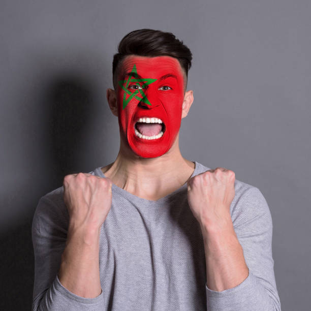 istock Young man with Morocco flag painted on his face 953058344