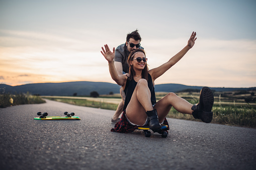 Hipster couple skating on the road