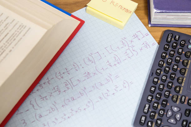 istock A student is doing math homework with a calculator and an open book on a wood table composition 953058994