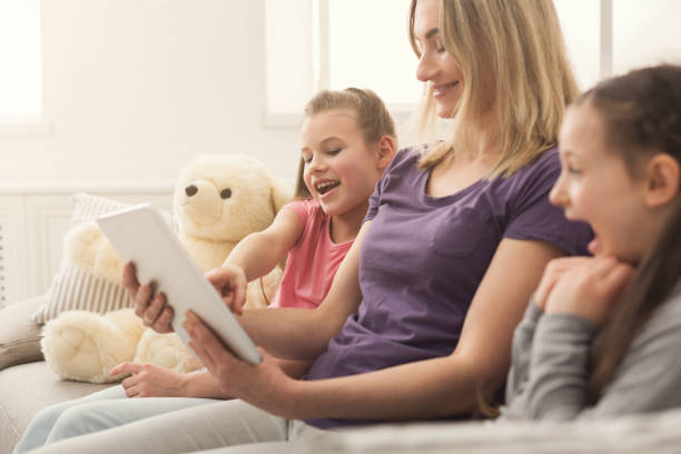 istock Happy beautiful woman and her daughters using digital tablet 953062568