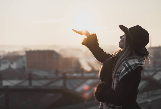 chica en un abrigo negro sobre la ciudad quiere tocar el sol - heaven women sunrise inspiration fotografías e imágenes de stock