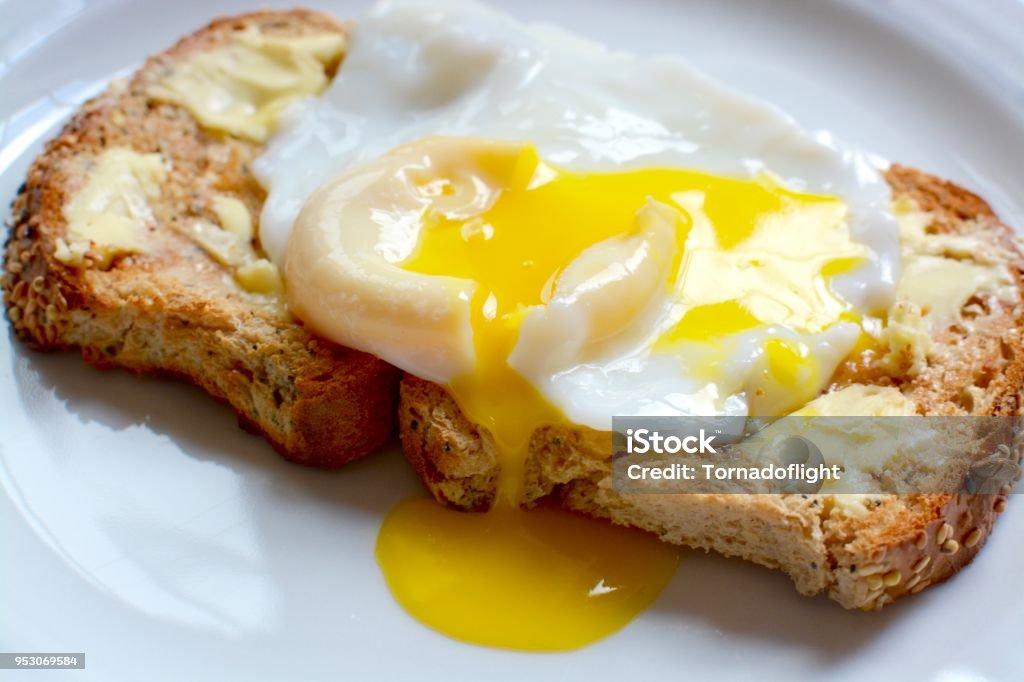 Poached egg on toast Runny poached egg on seeded brown toast Egg - Food Stock Photo