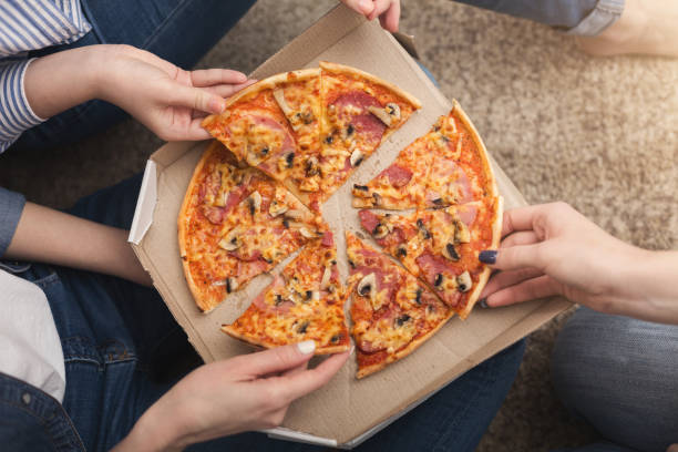istock Closeup of girls hands taking pizza slices 953073708