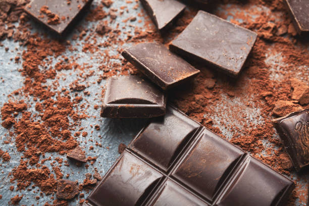 istock Crushed chocolate bar pieces and cocoa on gray background 953074024