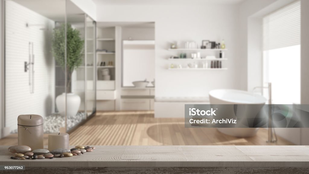 Wooden vintage table top or shelf with candles and pebbles, zen mood, over blurred minimalist bathroom with shower and walk-in closet, white architecture interior design Bathroom Stock Photo