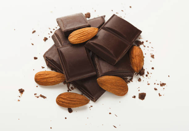 istock Broken dark chocolate bar and almonds isolated on white 953077334
