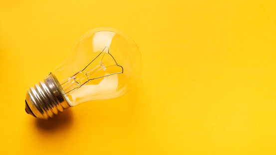 Light bulb on yellow background with copy space, side view, closeup. Idea, inspiration and innovation concept
