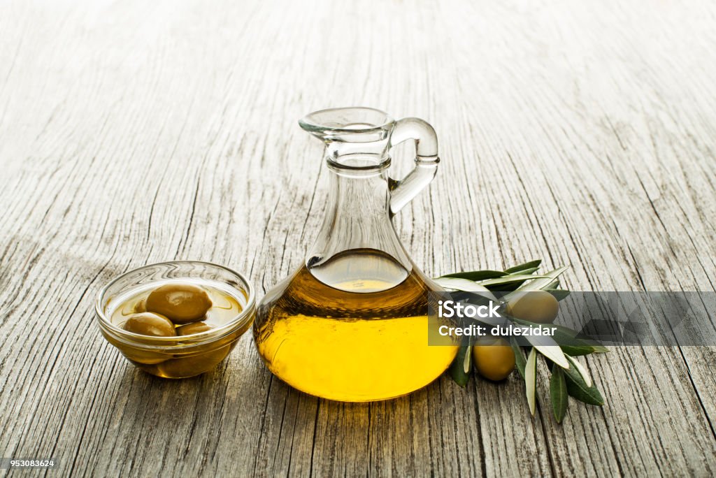 Olive oil Olive oil and olive branch on wooden table Olive Oil Stock Photo