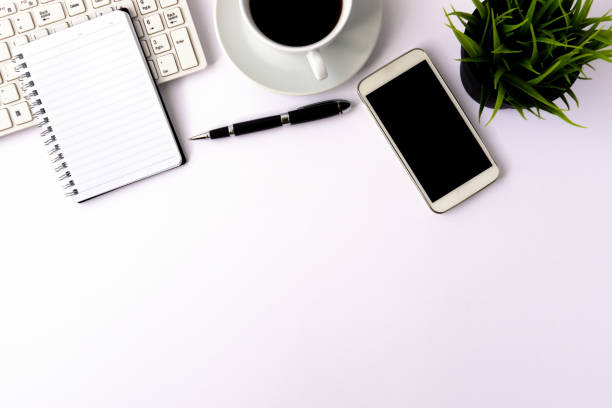 istock White office desk table with keyboard, notepad, pen, cup of coffee and plant. 953084106